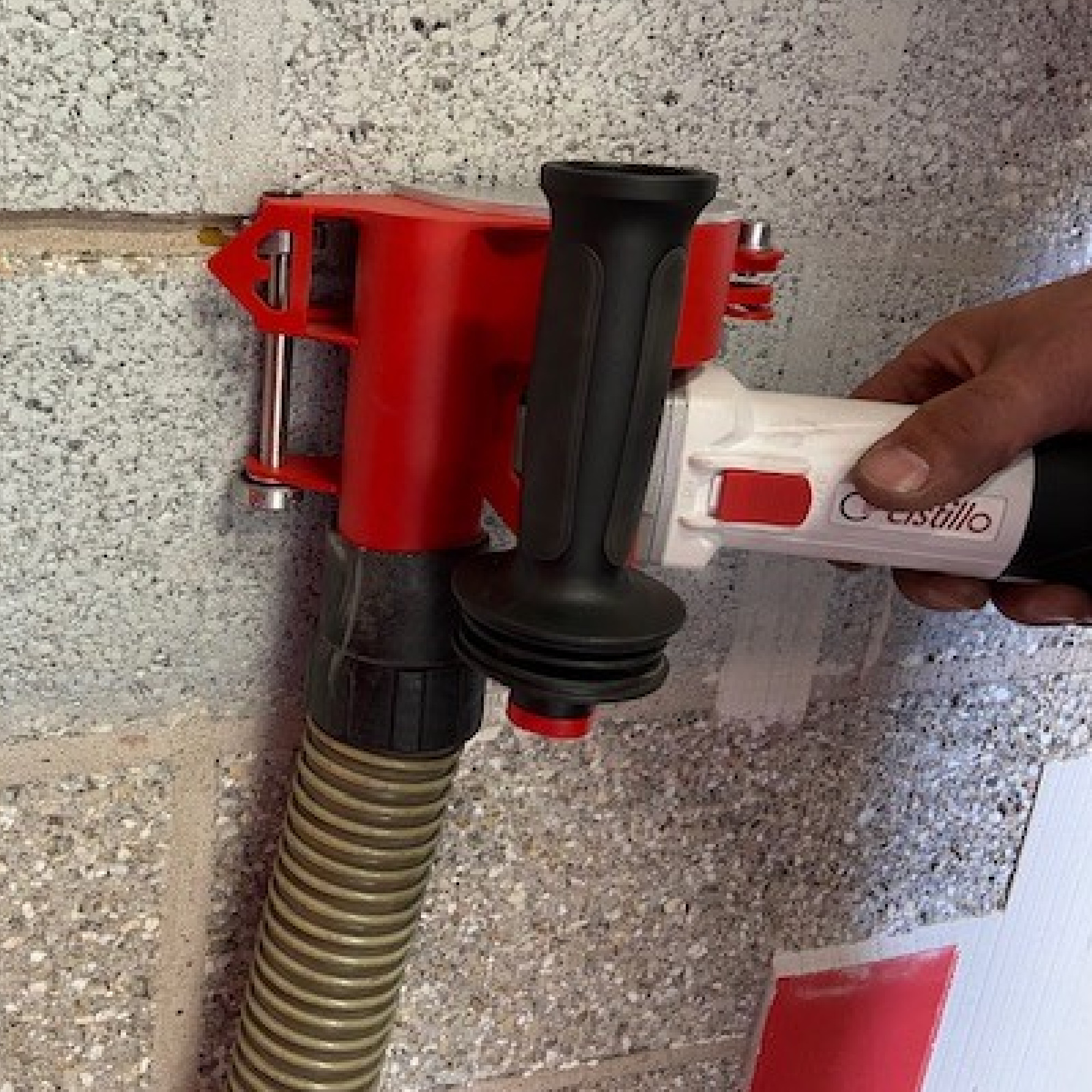 Fugenfräse Astillo im Einsatz an einer Betonwand, mit angeschlossenem Absaugschlauch, von einer Hand geführt.
