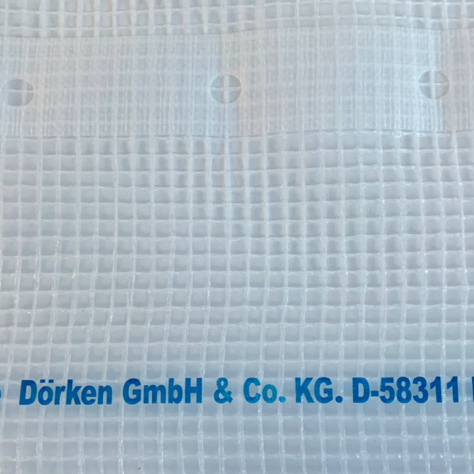 Ein durchsichtiger, strukturierter Stoff mit einem klaren, gitterartigen Muster. Am unteren Rand befindet sich in blauer Schrift der Text "Dörken GmbH & Co. KG. D-58311". Es sind mehrere Löcher sichtbar, vermutlich zur Befestigung oder Befestigung.